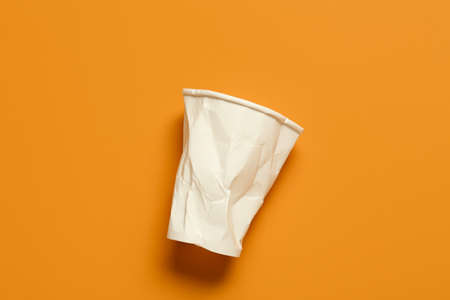 Crumpled blank paper cup on color backgroundの写真素材