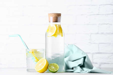 Bottle and glass of tasty cold lemonade on light backgroundの写真素材