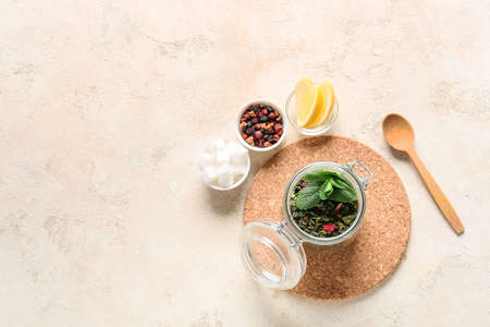 Composition with different dry tea, lemon and sugar on light background