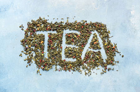 Word TEA made of dry green leaves on color backgroundの写真素材