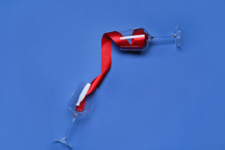 Wineglasses with red ribbon on color backgroundの写真素材