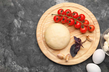 Board with dough and ingredients for preparing pizza on grunge backgroundの写真素材