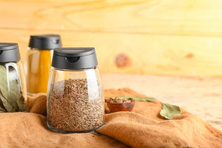 Jars with different spices on wooden background