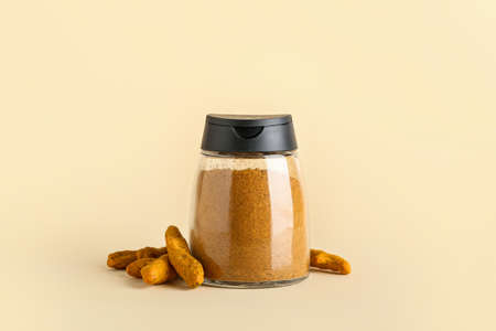 Jar of turmeric powder and roots on color backgroundの写真素材