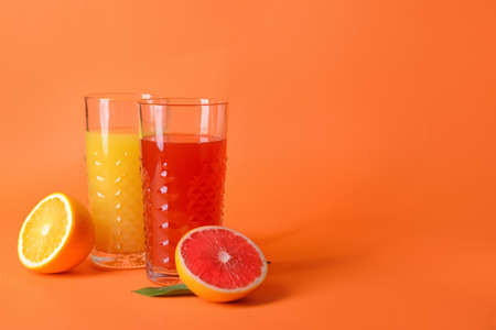 Glasses of orange and grapefruit juice on color backgroundの写真素材