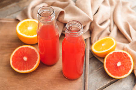 Bottles of grapefruit juice on wooden backgroundの写真素材