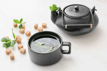 Teapot and cup of hot green tea on light backgroundの写真素材