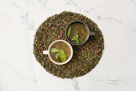 Composition with cups of green tea and dry leaves on light backgroundの写真素材