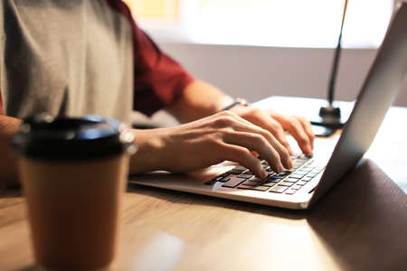 Young man using laptop at home, closeup