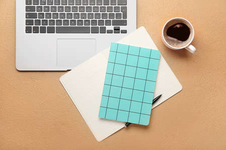 Notebooks, cup of coffee and laptop on color backgroundの写真素材