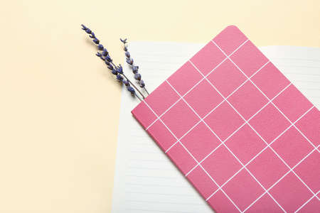 Notebooks and lavender flowers on color background