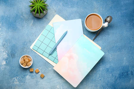 Composition with notebooks, pen, sugar cubes and cup of coffee on color background