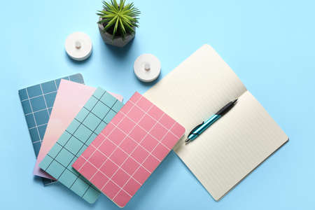 Composition with notebooks, pen and houseplant on color background