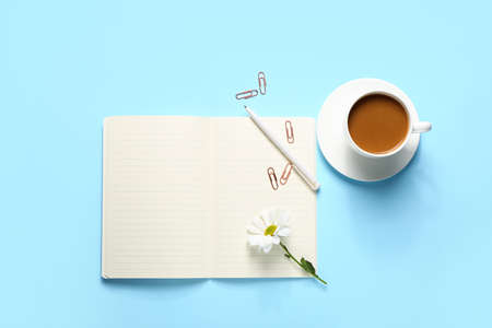 Composition with notebook, stationery, cup of coffee and flower on color background
