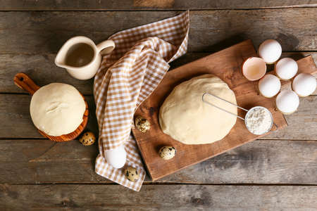 Composition with fresh dough, flour and eggs on wooden background