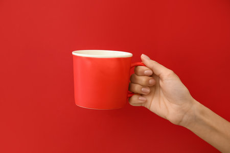 Hand with cup on color backgroundの写真素材