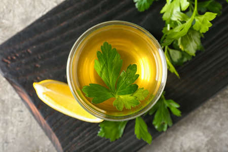 Board with cup of hot tea, parsley and lemon on grunge background, closeupの写真素材