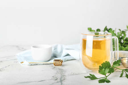 Cup of hot tea, parsley and honey on light backgroundの写真素材