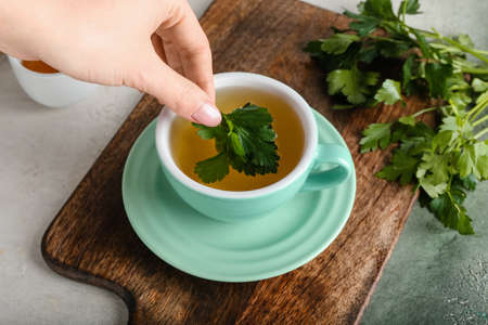 Woman preparing hot tea with parsley on color background, closeupの写真素材