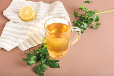 Cup of hot tea, parsley and lemon on color backgroundの写真素材