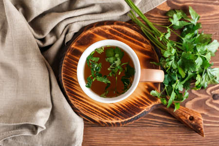 Board with cup of hot tea and parsley on wooden backgroundの写真素材