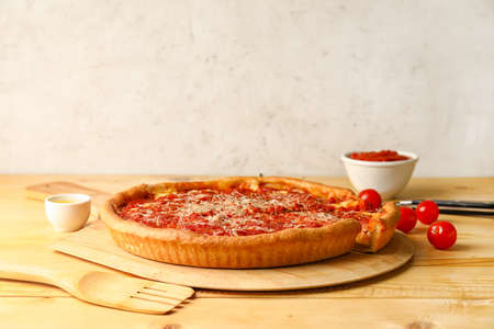 Board with tasty Chicago-style pizza on wooden tableの写真素材