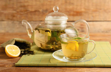 Cup and teapot of green tea with lemon on wooden backgroundの写真素材