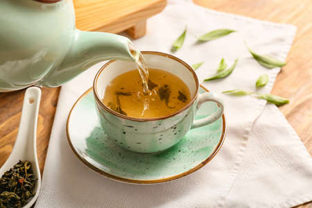 Pouring of green tea from teapot into cup, closeupの写真素材
