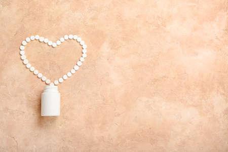 Heart made of vitamin K pills on color backgroundの写真素材
