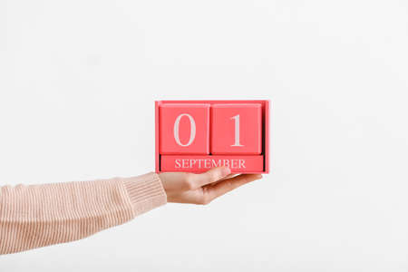 Woman holding cube calendar with date SEPTEMBER 1 on white backgroundの写真素材