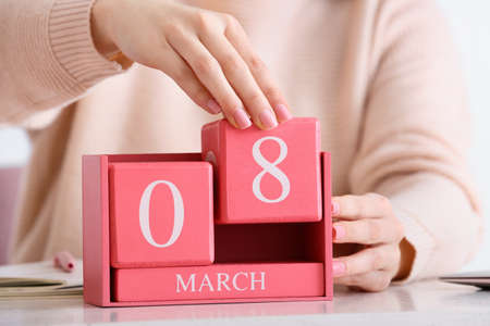 Woman holding cube calendar with date MARCH 8 on table in room, closeupの写真素材
