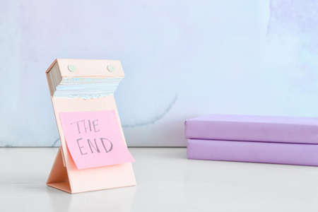 Tear-off calendar with text THE END and books on color background, closeupの写真素材
