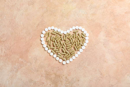 Heart made of vitamin K pills on color backgroundの写真素材