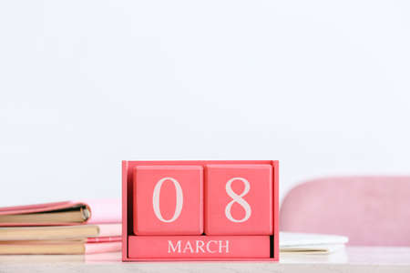 Cube calendar with date MARCH 8 and books on table in room, closeupの写真素材