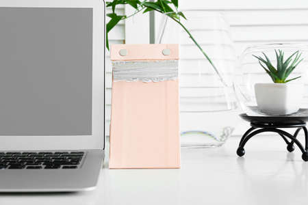 Tear-off calendar and laptop on table in room, closeup