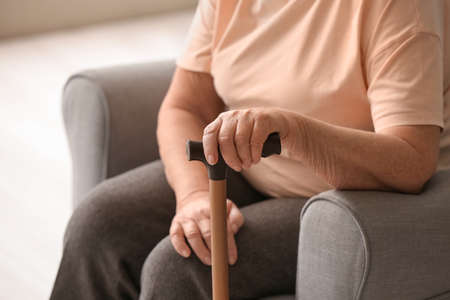 Elderly woman with walking stick at homeの写真素材
