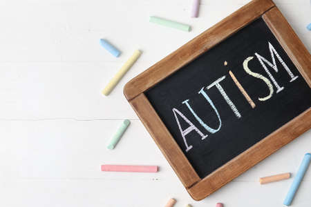 Chalk board with word AUTISM on white wooden backgroundの写真素材