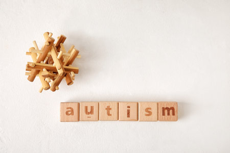 Word AUTISM made of cubes and toy on white background