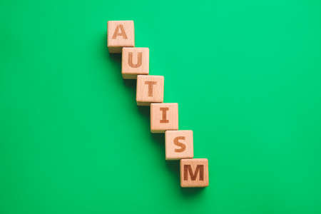 Word AUTISM made of cubes on color background