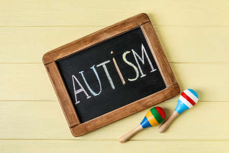 Chalk board with word AUTISM and maracas on color wooden backgroundの写真素材