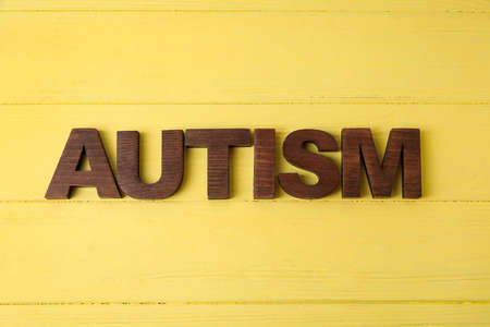 Word AUTISM on color wooden background