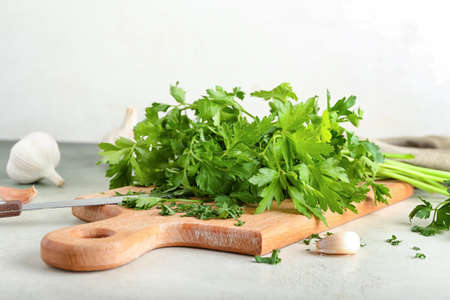 Board with fresh parsley and garlic on light backgroundの写真素材