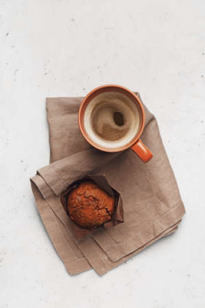 Cup of coffee and muffin on light background