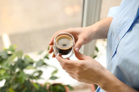 Woman with cup of delicious turkish coffee near window indoors, closeup