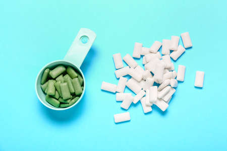 Scoop with tasty chewing gums on color background