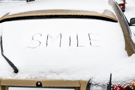 Word SMILE written on snow covered car windowの写真素材