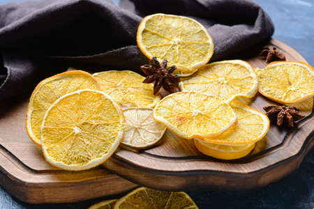 Board with dried citrus fruits on color background, closeup