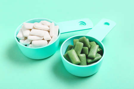 Scoops of tasty chewing gums on color background
