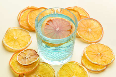 Glass of cocktail with dried orange slices on light backgroundの写真素材