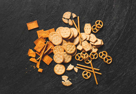 Tasty different crackers on dark background